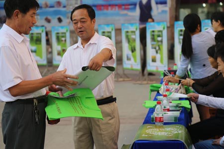 县科协主席包海建正在给群众发宣传图册及环保袋